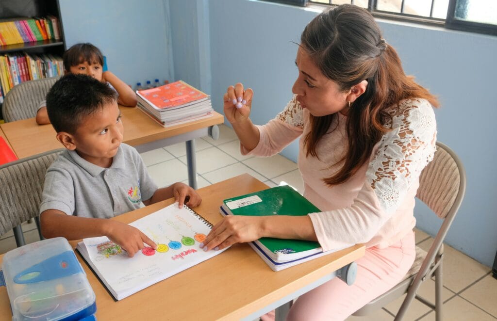 Teacher working one-on-one with a young learner at a classroom table