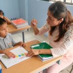 Teacher working one-on-one with a young learner at a classroom table
