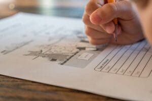 Hand filling in a printed ESL worksheet with a pencil